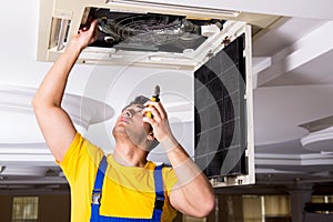 The repairman repairing ceiling air conditioning unit