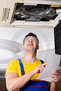 The repairman repairing ceiling air conditioning unit