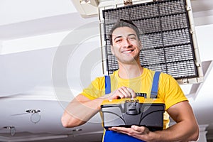 The repairman repairing ceiling air conditioning unit