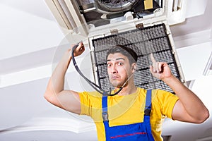 The repairman repairing ceiling air conditioning unit