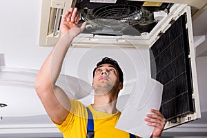 The repairman repairing ceiling air conditioning unit