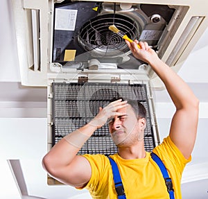 Repairman repairing ceiling air conditioning unit