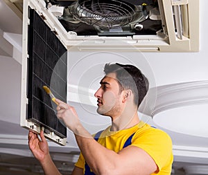 Repairman repairing ceiling air conditioning unit