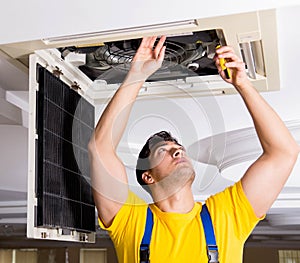 Repairman repairing ceiling air conditioning unit