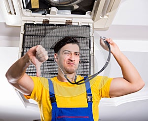 Repairman repairing ceiling air conditioning unit