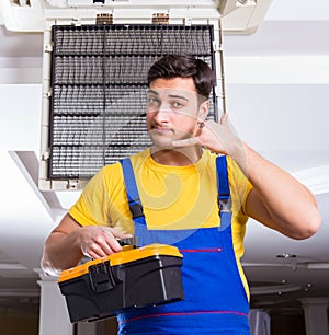 Repairman repairing ceiling air conditioning unit