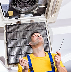 Repairman repairing ceiling air conditioning unit