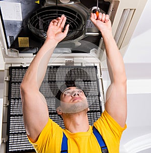 Repairman repairing ceiling air conditioning unit