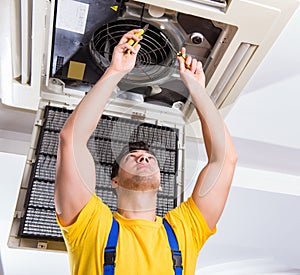 Repairman repairing ceiling air conditioning unit