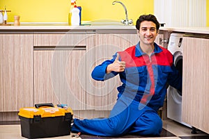 Repairman repairing washing machine in the kitchen