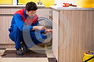 Repairman repairing washing machine in the kitchen