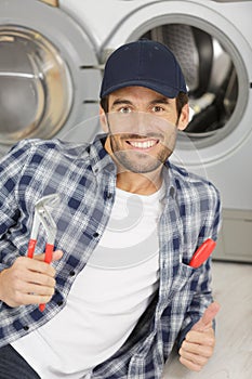 Repairman repairing washing machine in kitchen