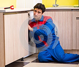 Repairman repairing washing machine in the kitchen