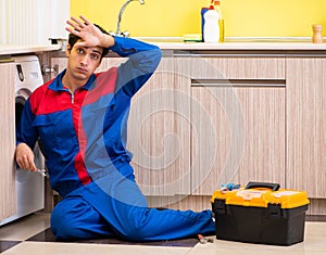 Repairman repairing washing machine in the kitchen