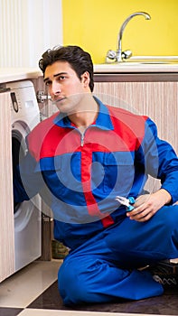 Repairman repairing washing machine in the kitchen