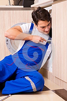 The repairman repairing washing machine at kitchen