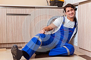 The repairman repairing washing machine at kitchen