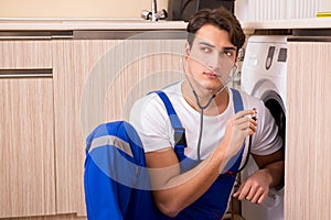 The repairman repairing washing machine at kitchen