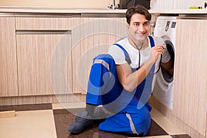 The repairman repairing washing machine at kitchen