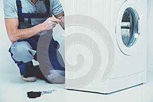 Repairman is repairing a washing machine on the white background