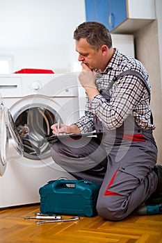 Repairman is repairing a washing machine on the white background