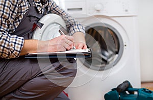 Repairman is repairing a washing machine on the white background photo