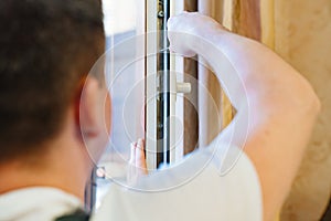 a repairman repairs, adjusts or installs metal-plastic windows in the apartment.