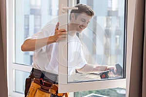 a repairman repairs, adjusts or installs metal-plastic windows in the apartment. glazing of balconies, loggias, verandas