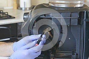 A repairman repairs a broken coffee maker