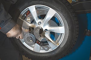 Repairman replaces and balancing car tyre wheel on special balancer equipment tool in car repair service