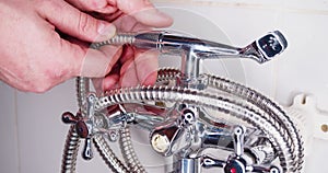 Repairman screwing the shower hose to the faucet. Hands of a plumber close-up.