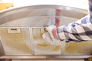 Repairman taking filthy aluminum mesh filter out of the cooker h