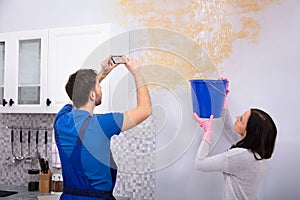 Repairman Taking Photo On Mobilephone Of Water Damage