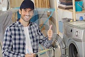 repairman with thumbs up by washing machine in kitchen