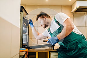 Repairman in uniform checks the oven, technician