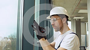 A repairman in uniform fixing pvc windows in new office