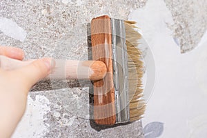 The repairman wets old wallpaper with water with a brush - a method of removing old wallpaper from the wall.