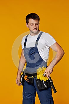 Repairman worker in yellow hard hat and uniform holding hammer.