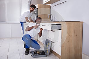 Repairmen Fixing The Wooden Cabinet In The Kitchen