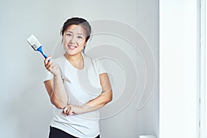 Repairs in the apartment, the girl makes repairs in the apartment, paint the walls with a brush, the girl holds a brush