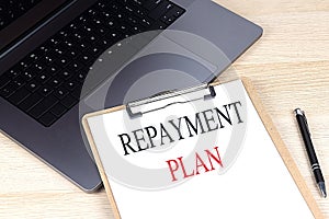 REPAYMENT PLAN text on clipboard on laptop
