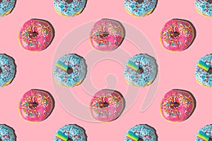 Repeating pattern of pink and blue donuts on a pink background. Flat lay