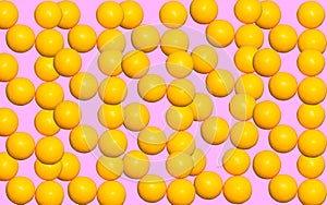 Repeating pattern with round yellow vitamins ascorbic acid on a pink background. Prevention of colds