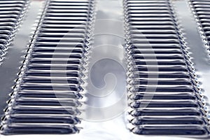 Repeating rows of cooling holes on a chrome metal surface of the hood of a modern car