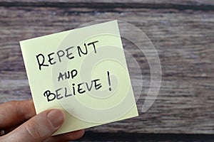 Repent and believe, handwritten message on a note in hand