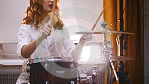 Repetition. Ginger girl plays drums raid . Portrait. Backlights.