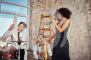 Repetition of multi ethnic jazz band in loft. Female African solist, saxophonist and drummer at loft. Jazz music and jam photo