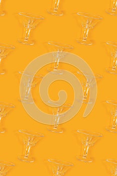 Repetitive pattern made of vintage crystal glasses on a yellow background.