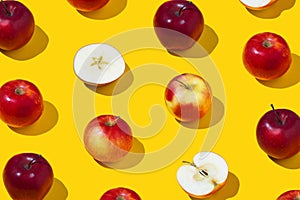 Repetitive pattern of whole and sliced apples on yellow background