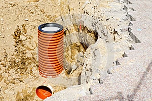 Replacement of communications on city street, vertical end of orange plastic pipe in sand trench